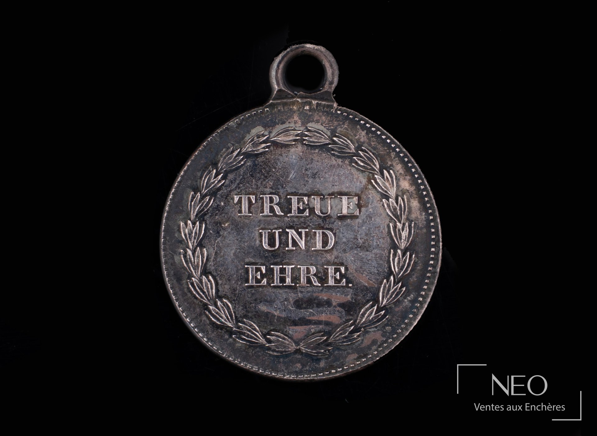 Revers d’une médaille suisse en argent avec la devise TREUE UND EHRE dans une couronne de feuillage.