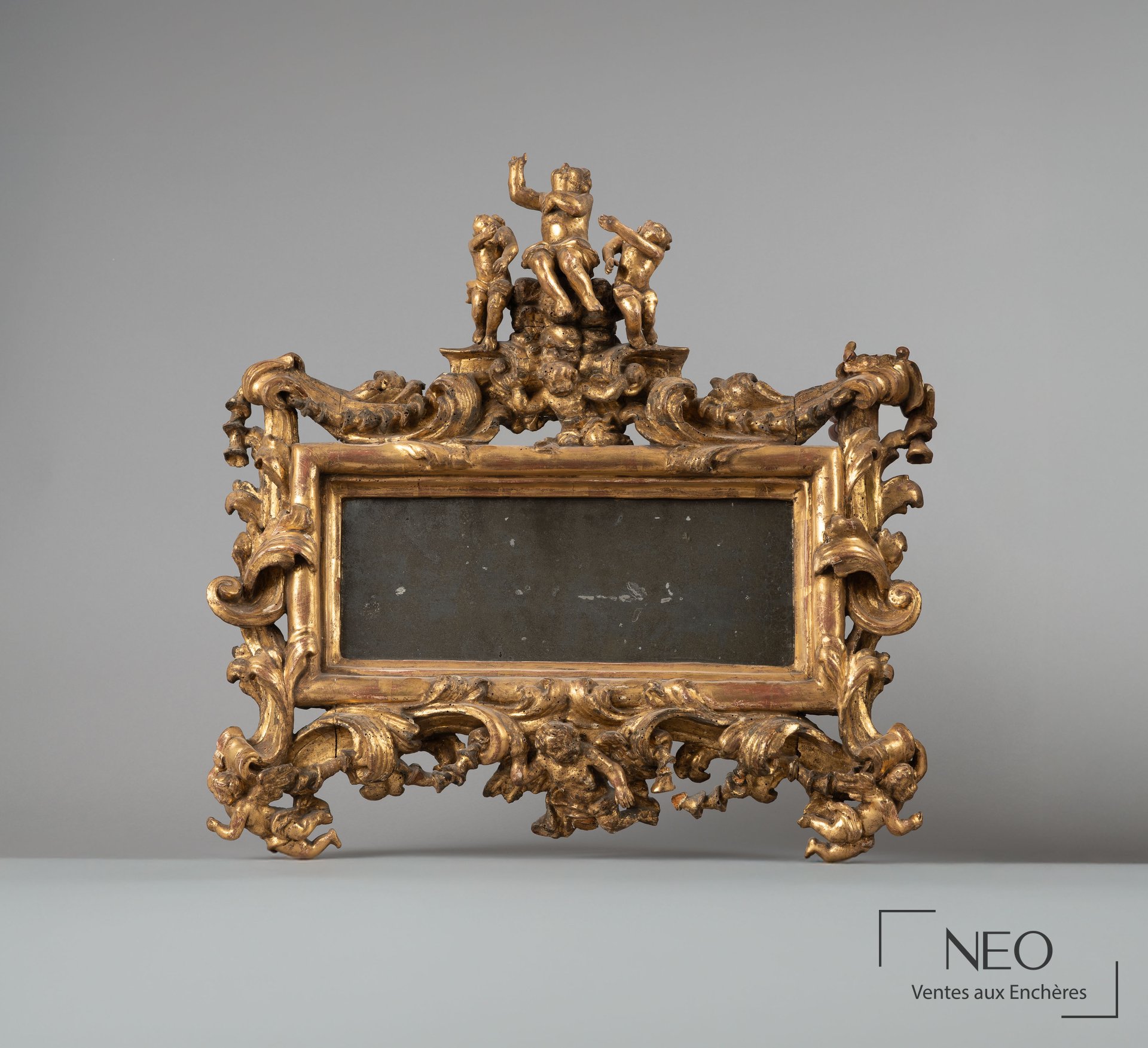 Miroir italien doré à fronton sculpté de putti