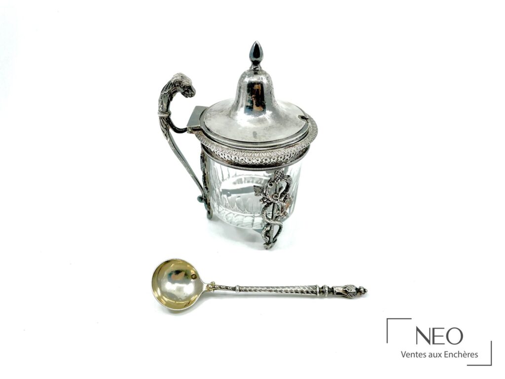 Moutardier en argent avec cuillère à sel présentés ensemble sur fond clair