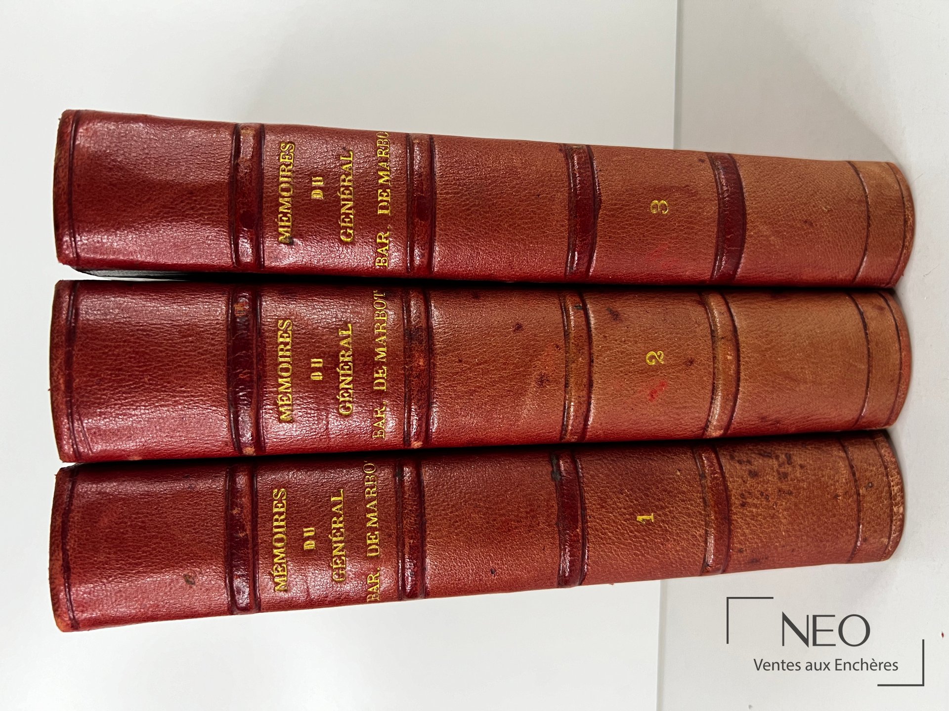Trois dos de volumes reliés en basane rouge avec titres dorés et numéros 1