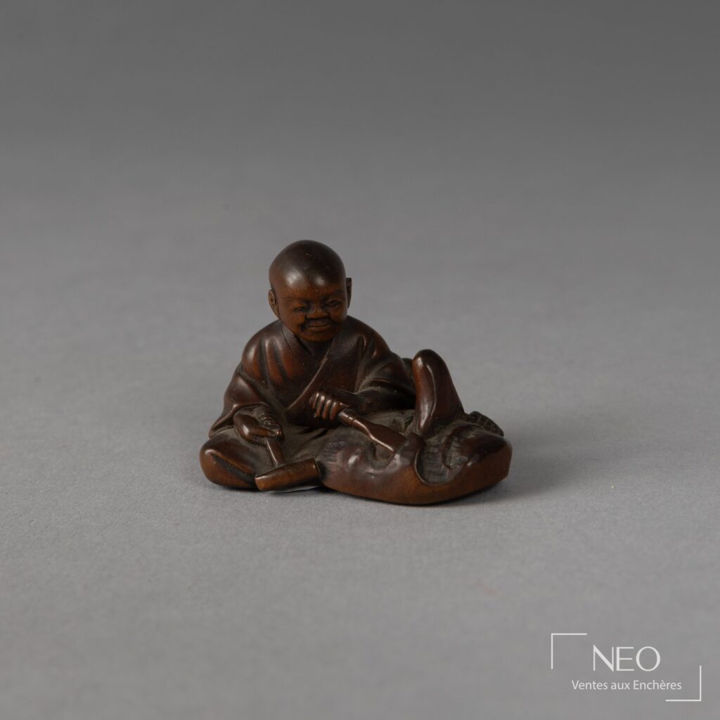 Netsuke en buis représentant un sculpteur de masque assis