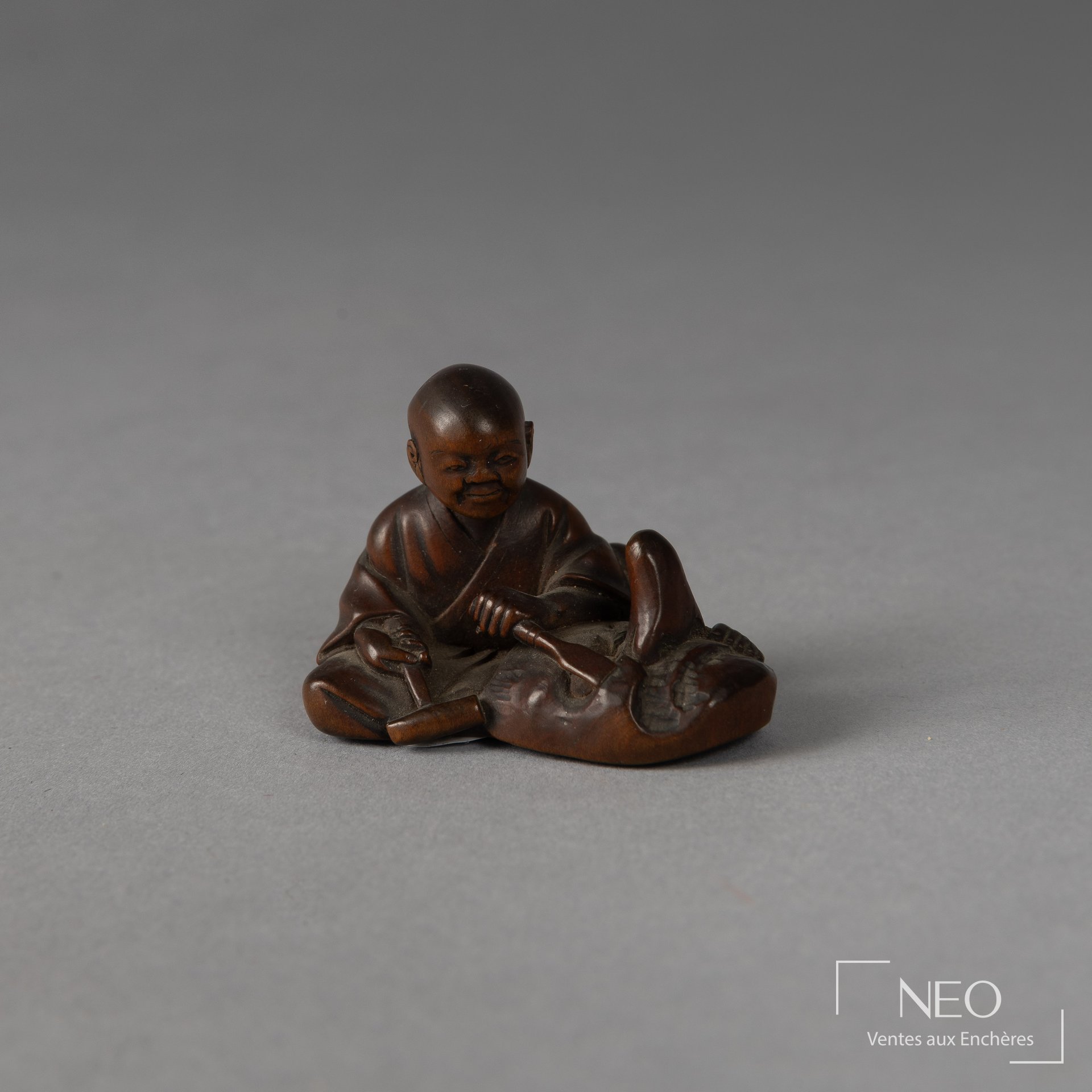 Netsuke en buis représentant un sculpteur de masque assis