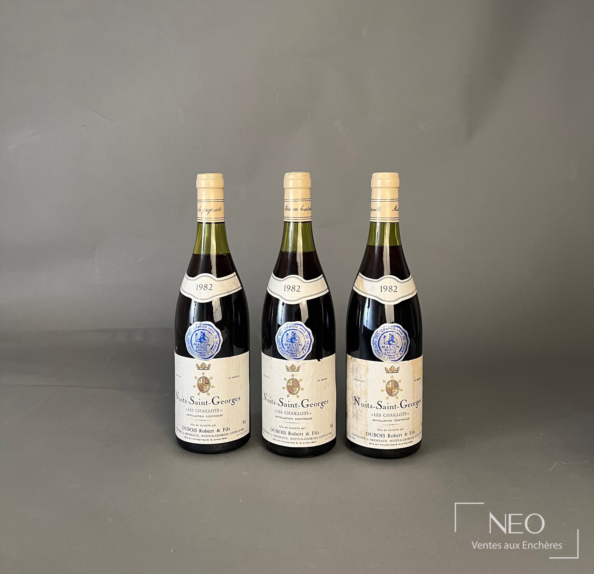 Trois bouteilles de Nuits-Saint-Georges Les Chaillots 1982 présentées de face.