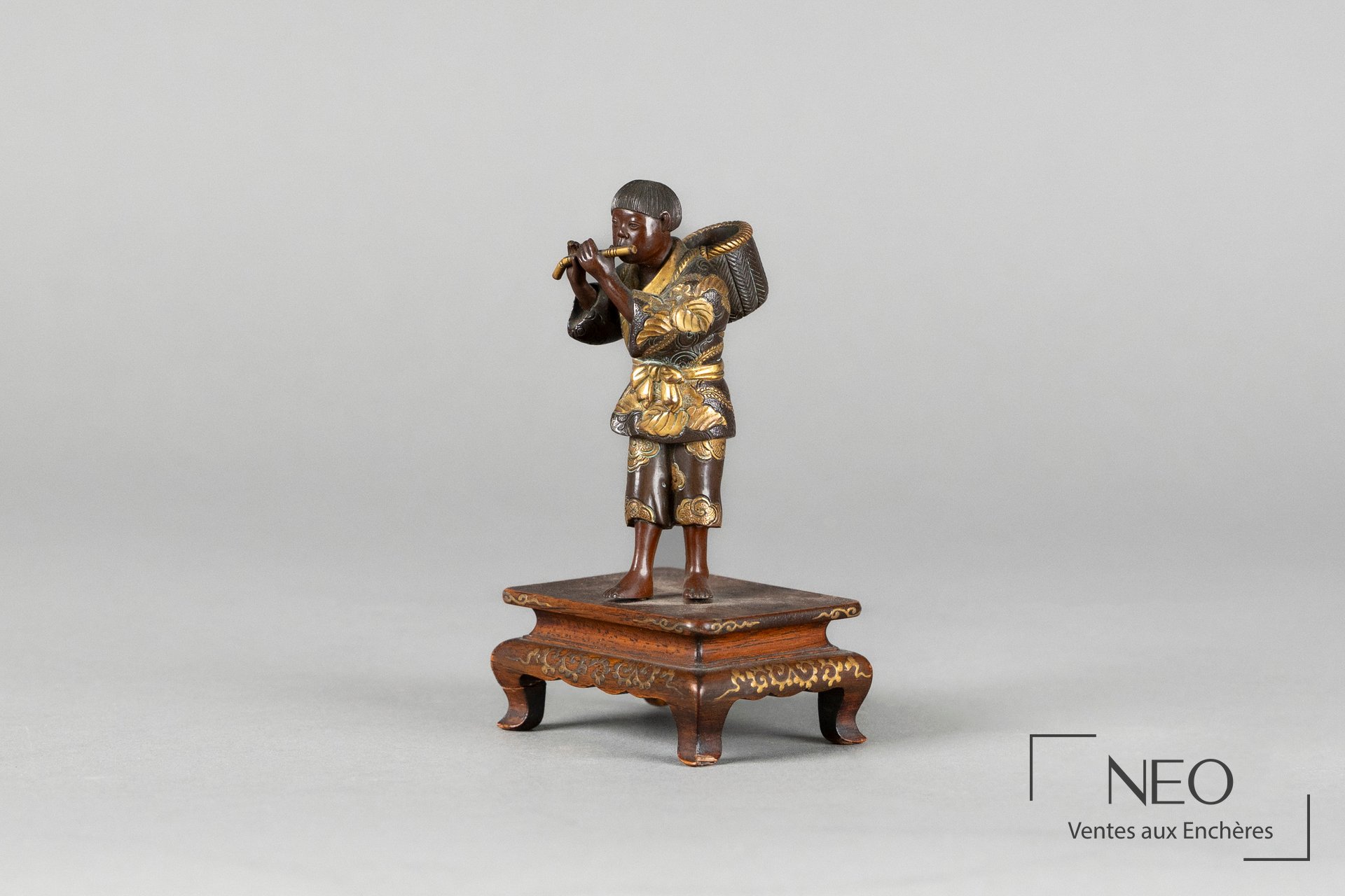 Okimono en bronze représentant un joueur de flûte sur son socle en bois décoré