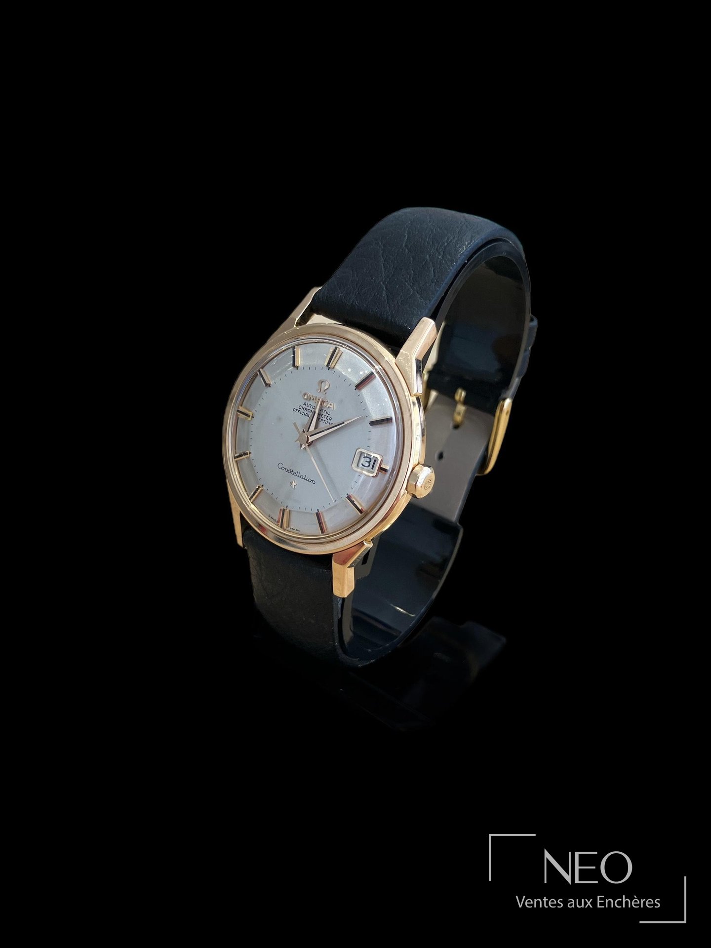 Montre Omega Constellation en or jaune avec cadran argenté et bracelet noir vue de face