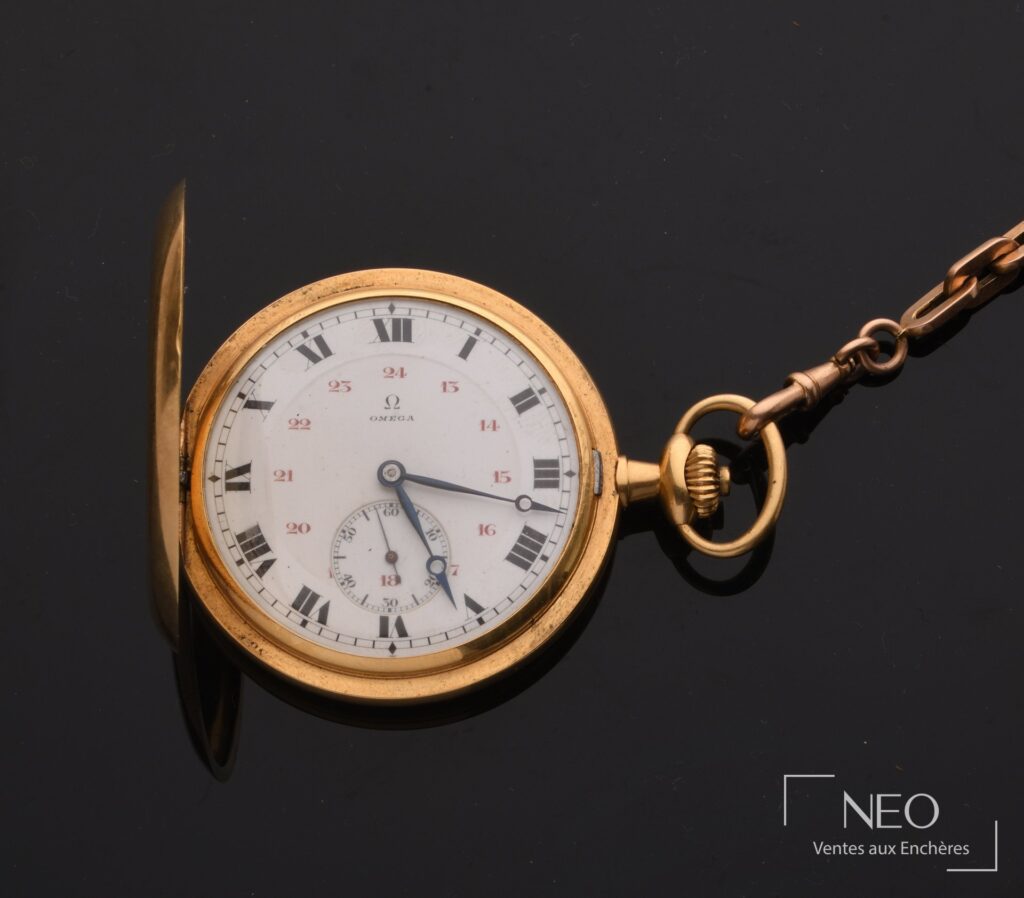 Montre à gousset OMEGA ouverte avec cadran émaillé blanc et chaîne en or rose.