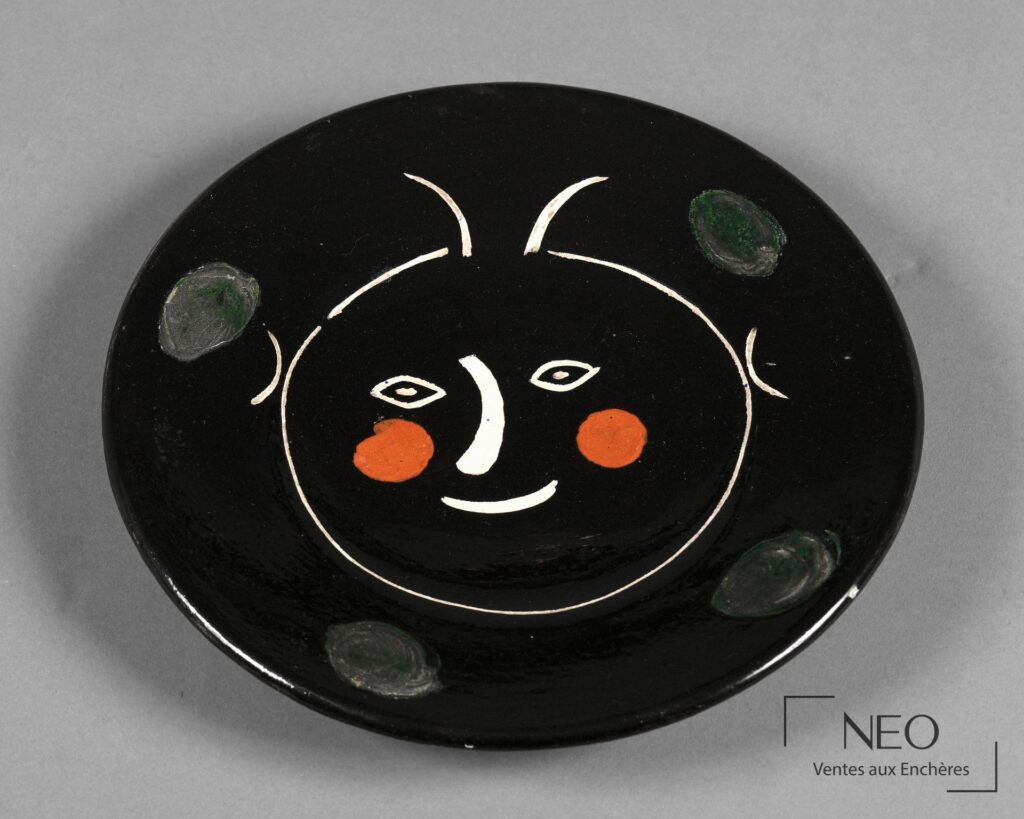 Assiette circulaire noire au visage stylisé