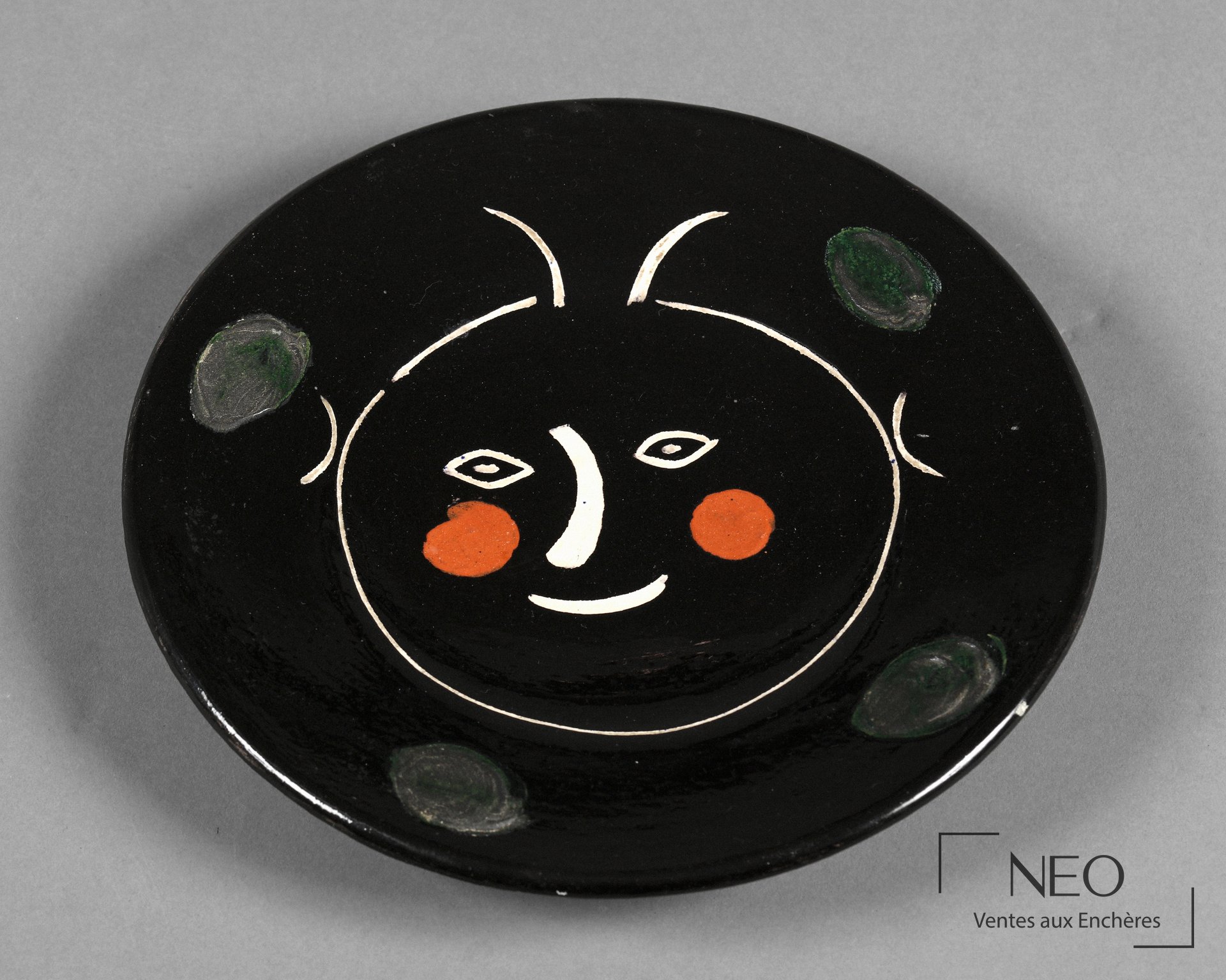 Assiette circulaire noire au visage stylisé