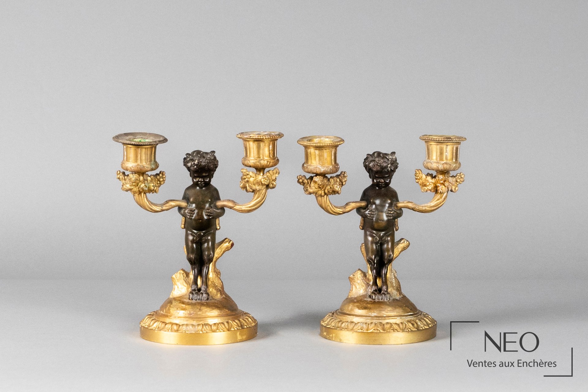 Paire de candélabres en bronze patiné et doré à décor de jeune faune