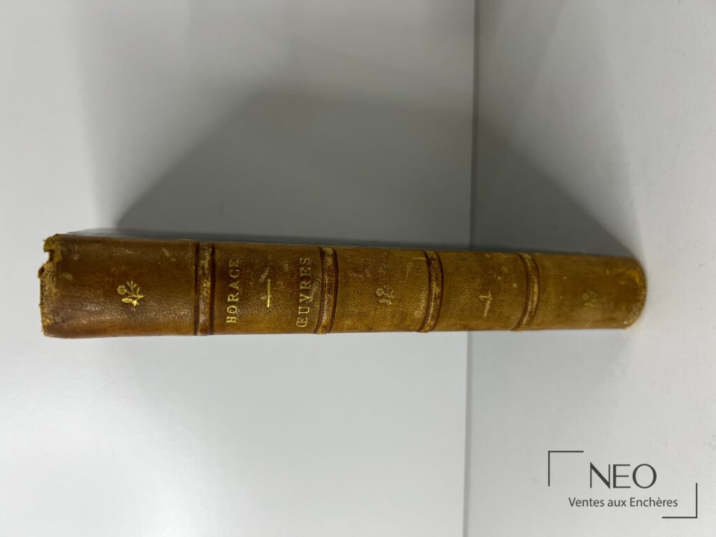Dos en demi basane d un livre ancien avec titres dorés et usure visible en coiffe.