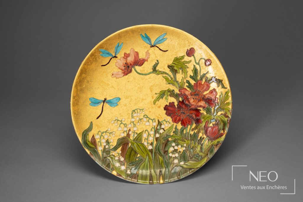 Assiette circulaire en faïence émaillée à décor floral et de libelules sur fond doré