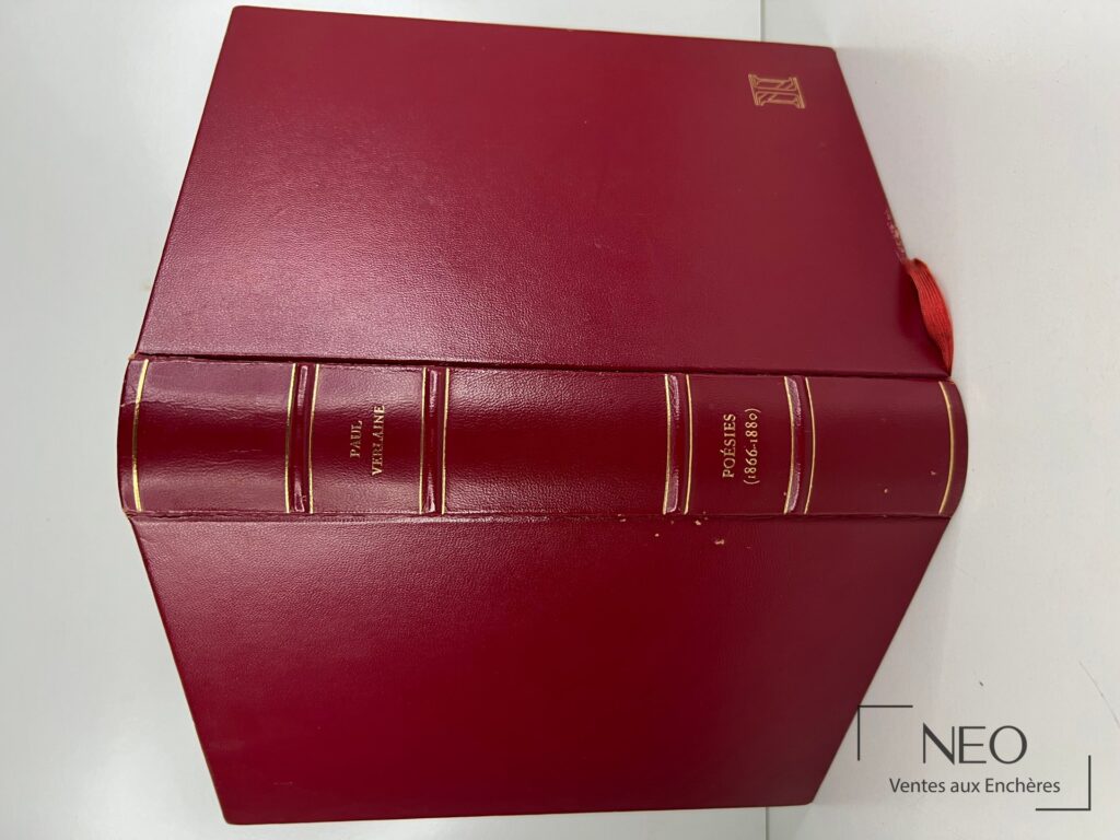 Livre relié rouge avec dos orné et ruban marque-page visible