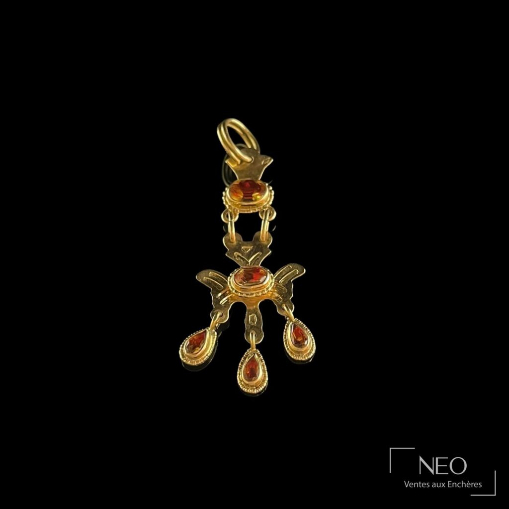 Pendentif articulé en or jaune retenant des pierres rouges facettées sur fond noir