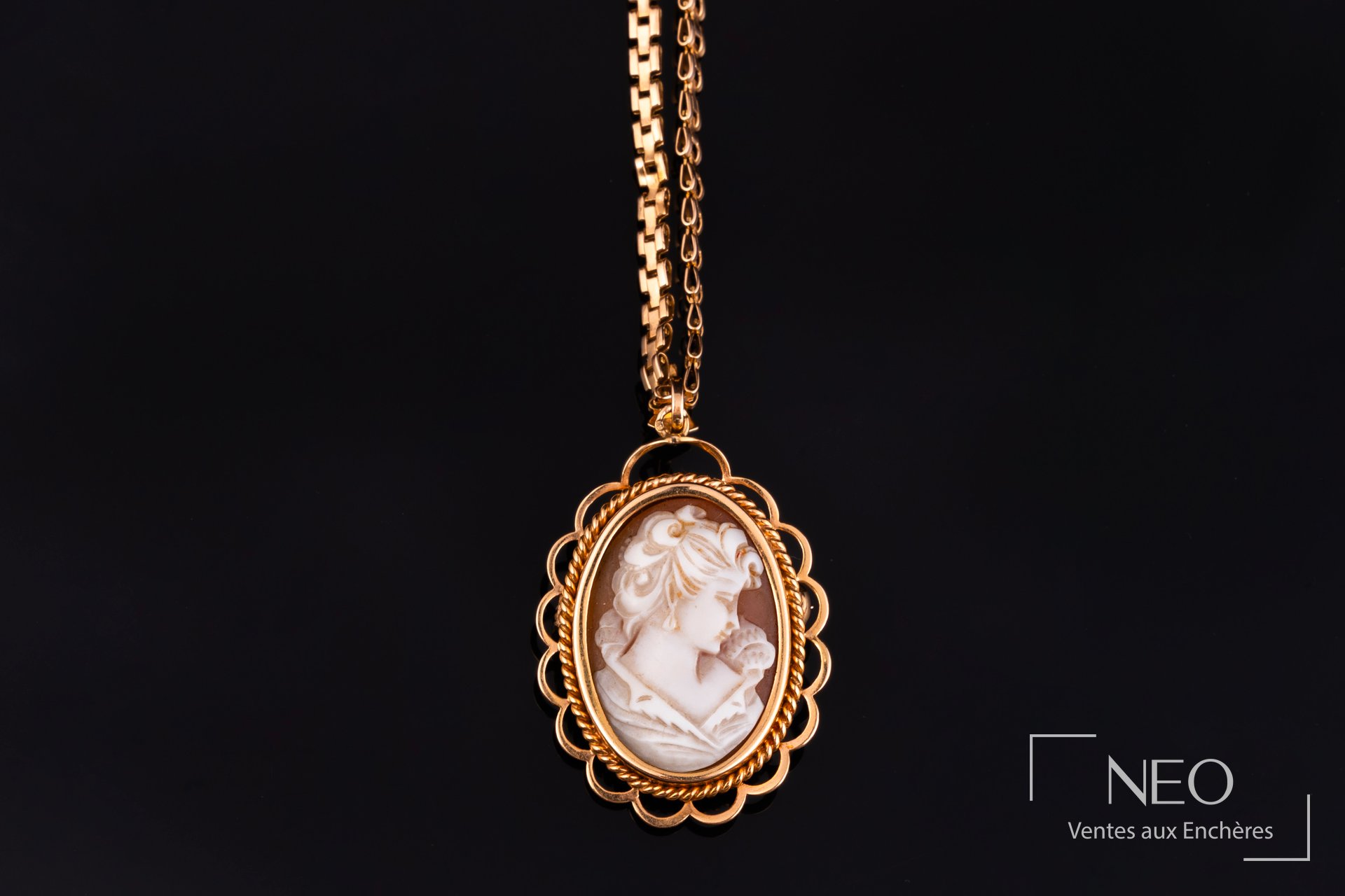 Pendentif camé ovale en or rose suspendu à une chaîne en or jaune sur fond noir