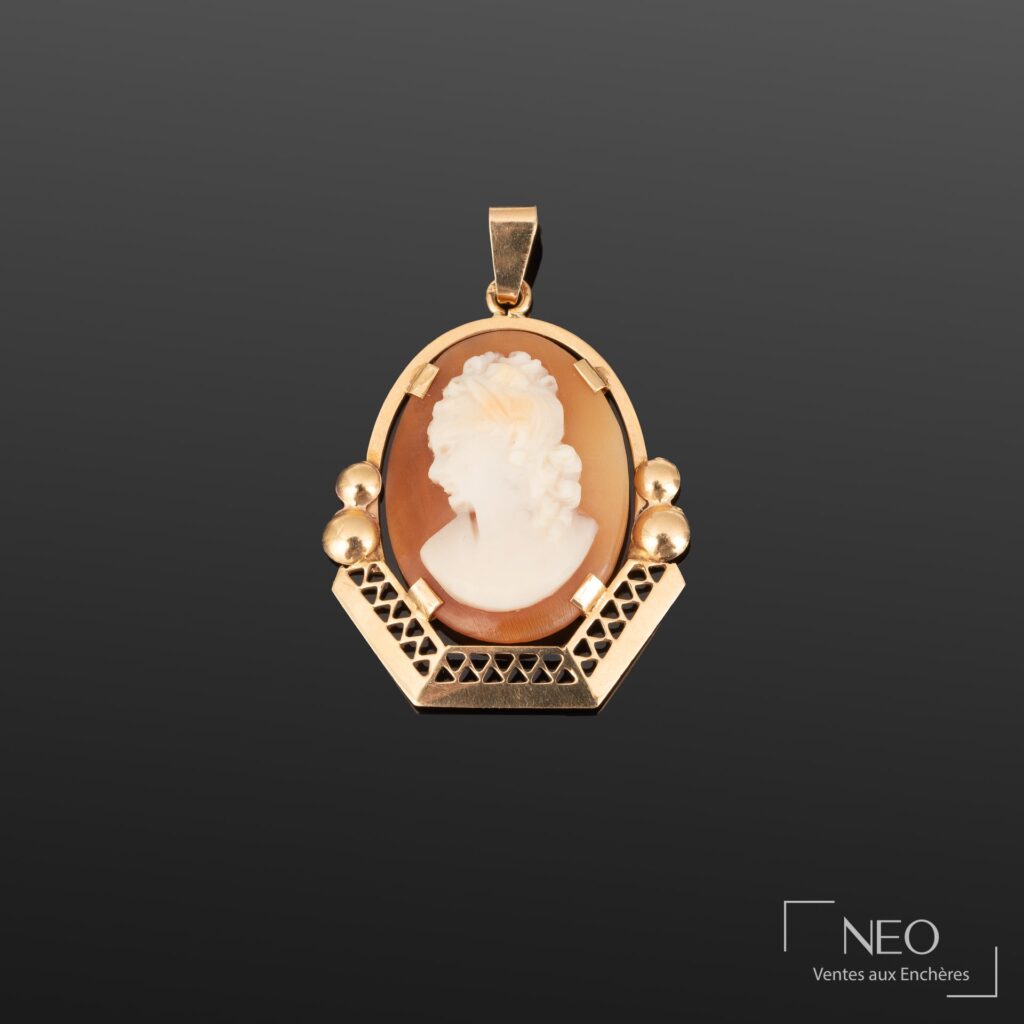 Pendentif en or jaune avec camée ovale à profil féminin sur fond brun.