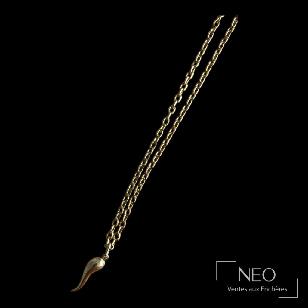 Pendentif cornicello en or jaune suspendu à une chaîne dorée sur fond noir