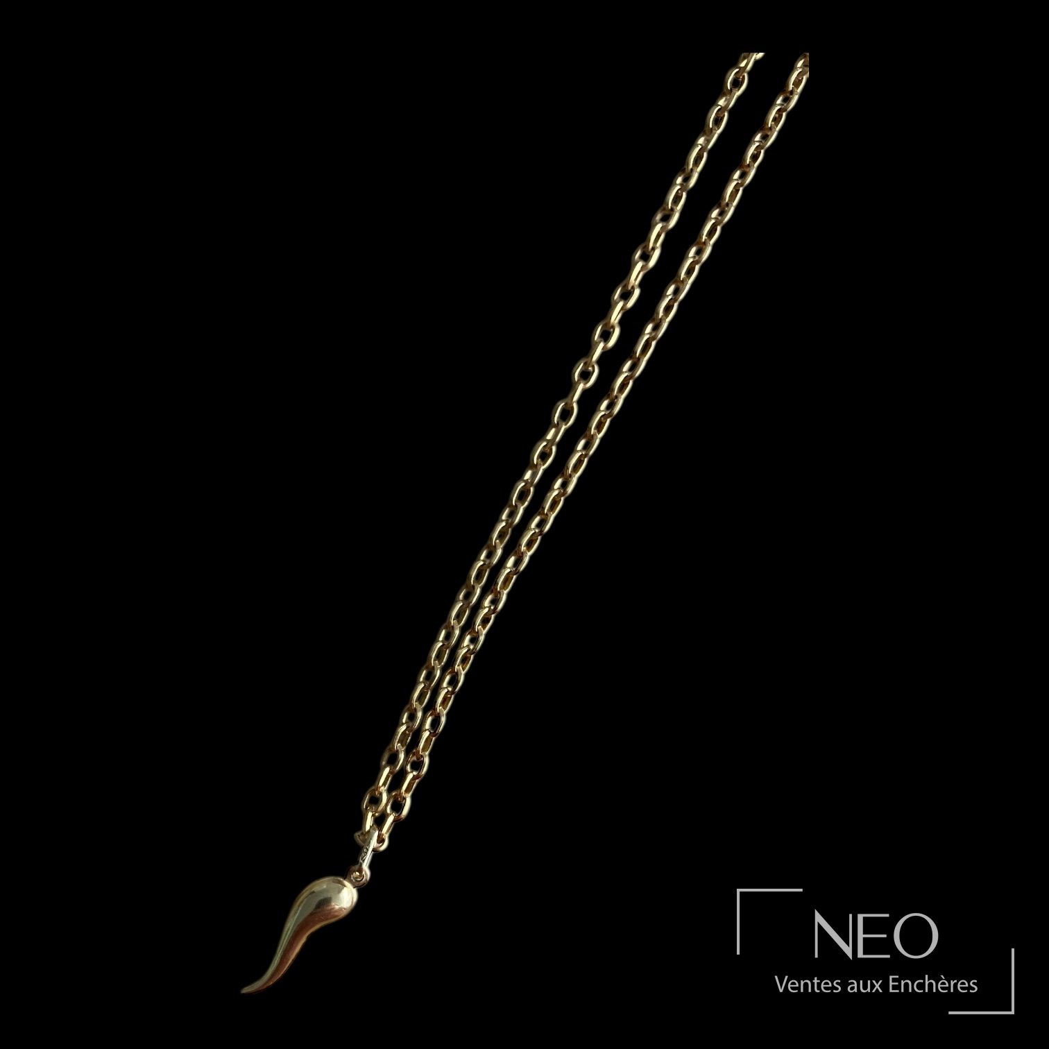 Pendentif cornicello en or jaune suspendu à une chaîne dorée sur fond noir