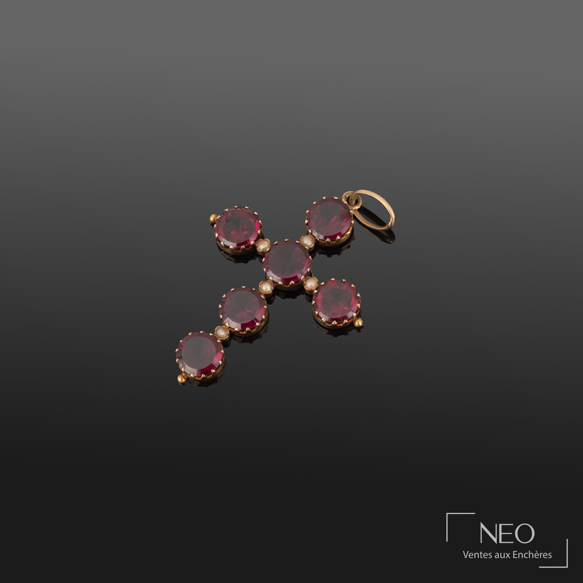 Pendentif croix latine en or jaune serti de grenats et de perles sur fond sombre