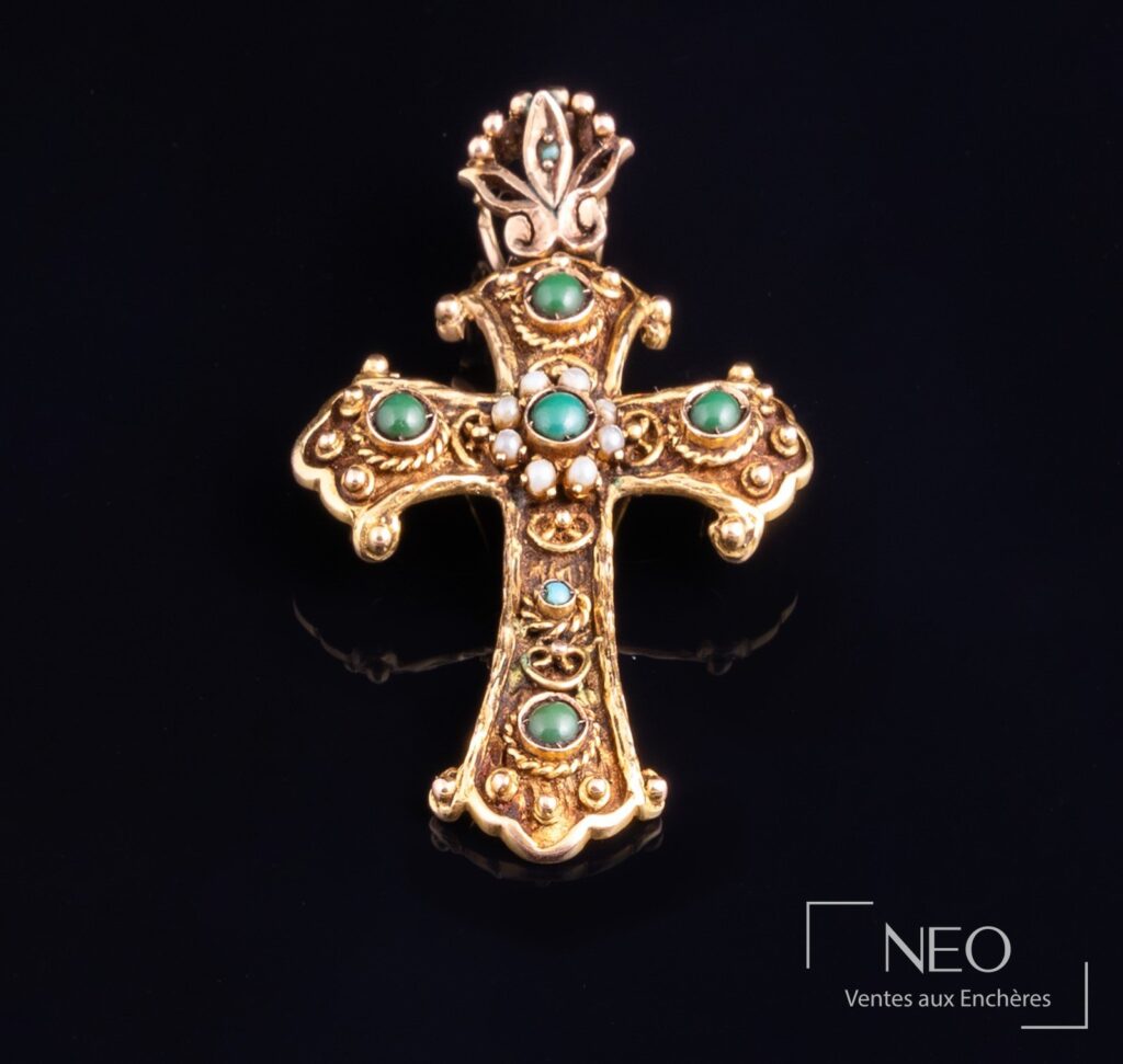 Pendentif croix en or jaune serti de cabochons verts et bleus sur fond noir