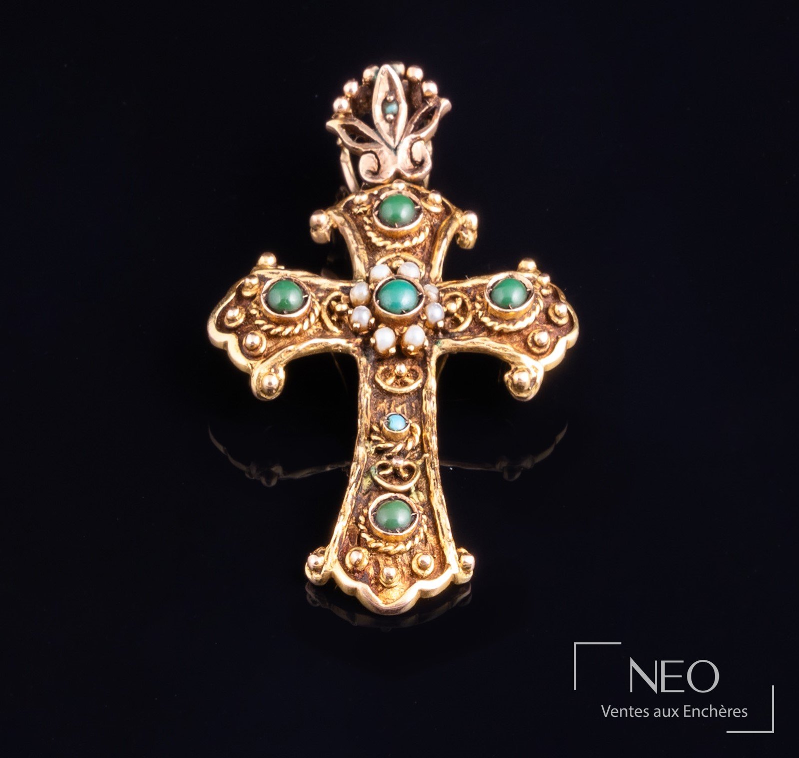 Pendentif croix en or jaune serti de cabochons verts et bleus sur fond noir