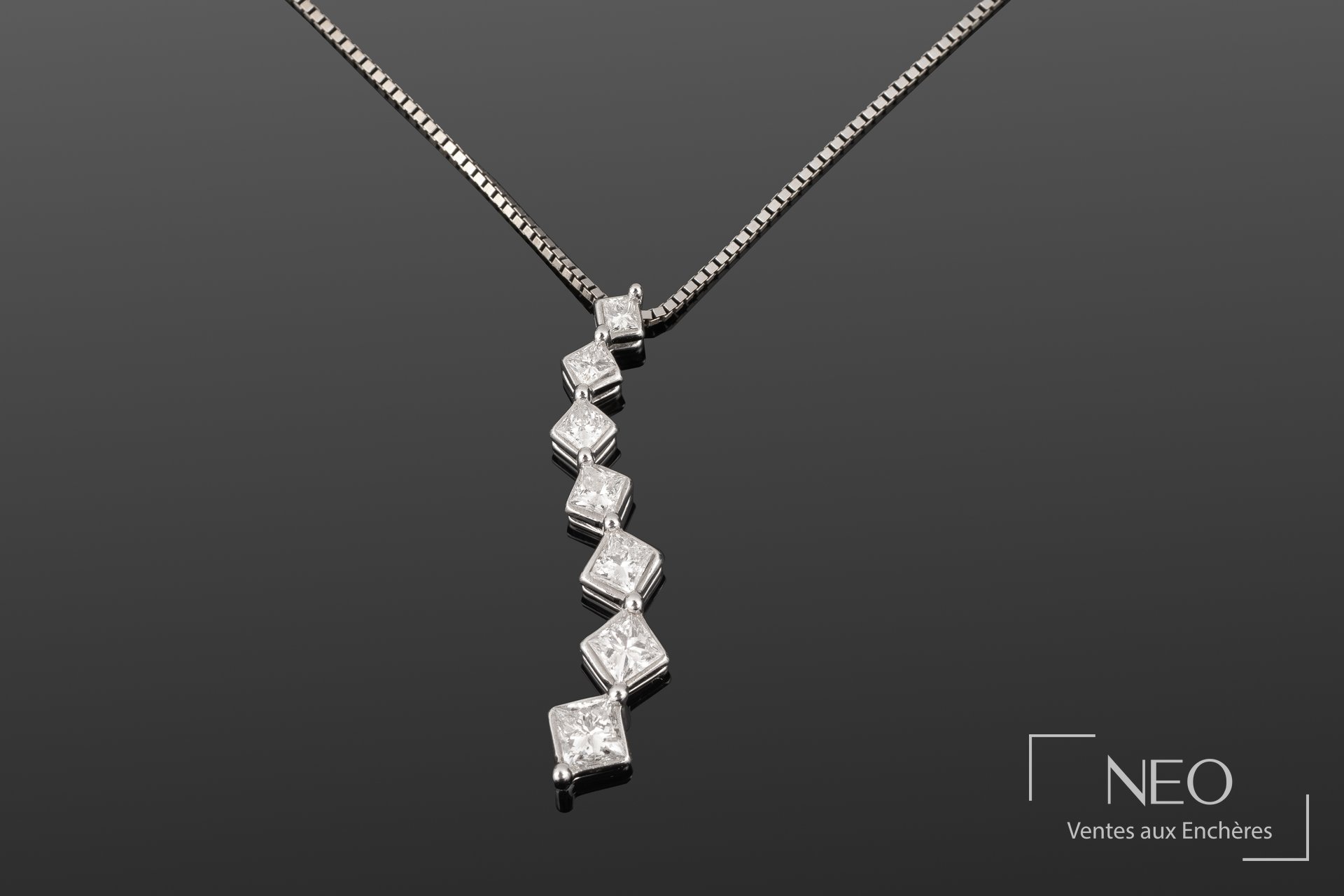 Pendentif en chute de sept diamants taille princesse sur chaîne en or blanc