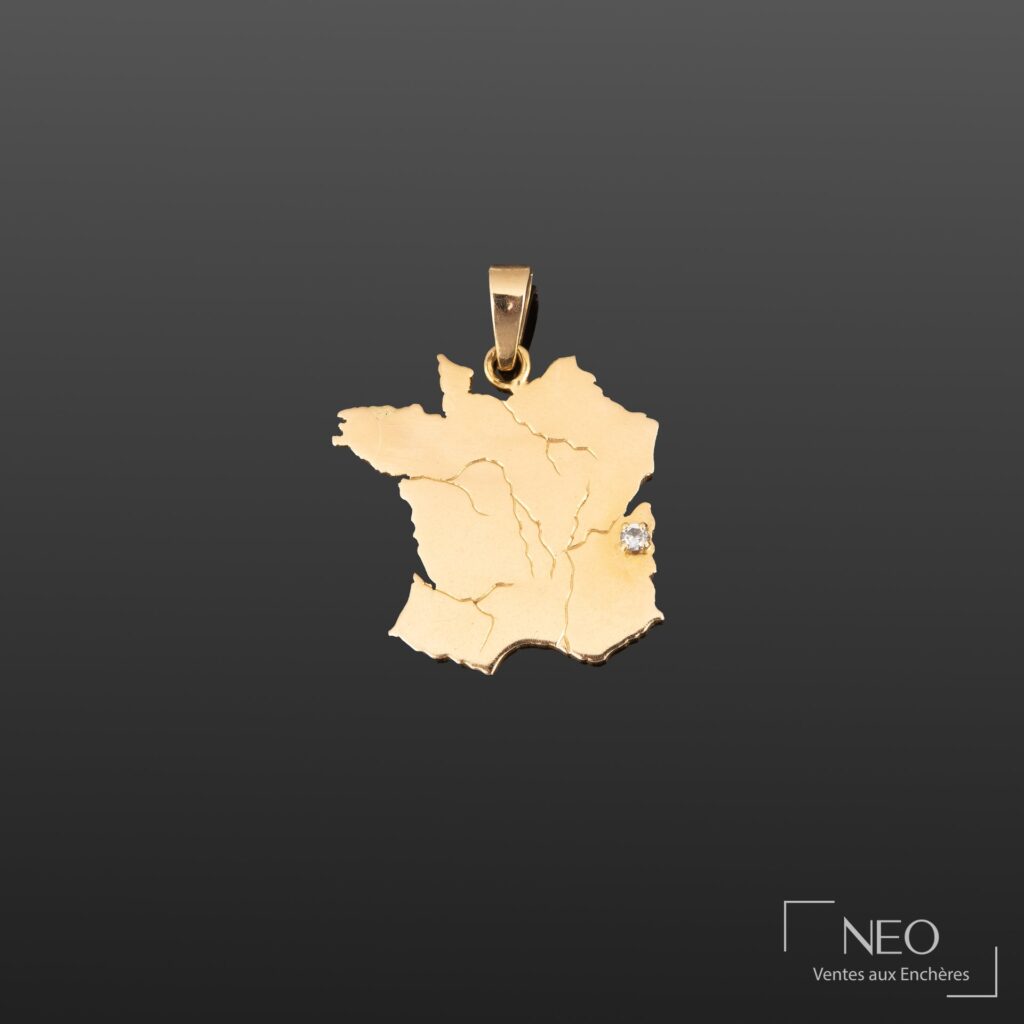 Pendentif en or jaune en forme de la France avec une petite pierre blanche sur le côté droit
