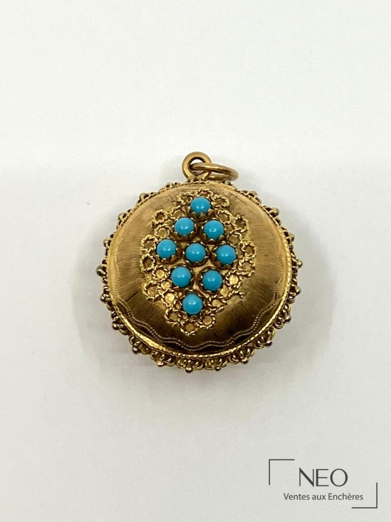 Pendentif rond en or jaune orné de turquoises au centre sur fond filigrané.