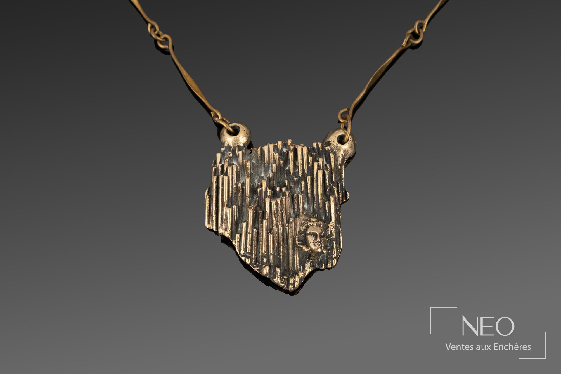 Pendentif sculptural en bronze doré avec visage et chaîne articulée