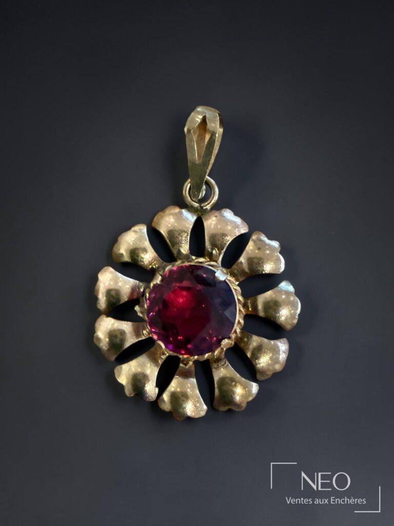 Pendentif en métal doré en forme de fleur avec pierre rouge facettée au centre