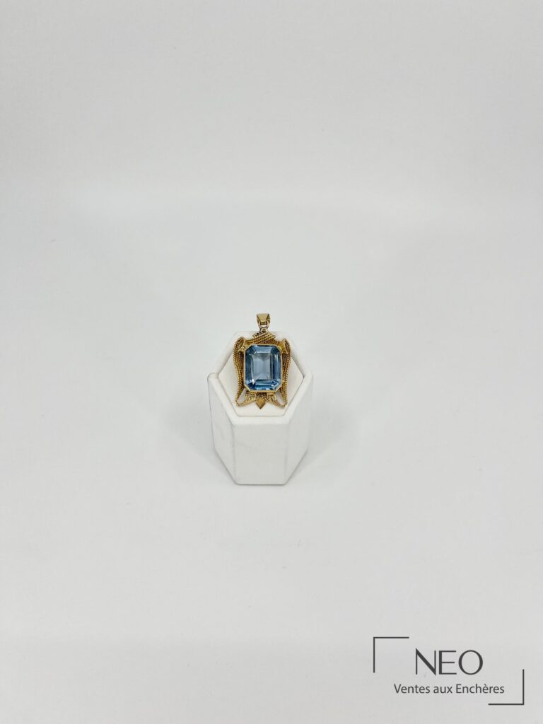 Pendentif en or jaune orné d’une aigue-marine rectangulaire sur support blanc