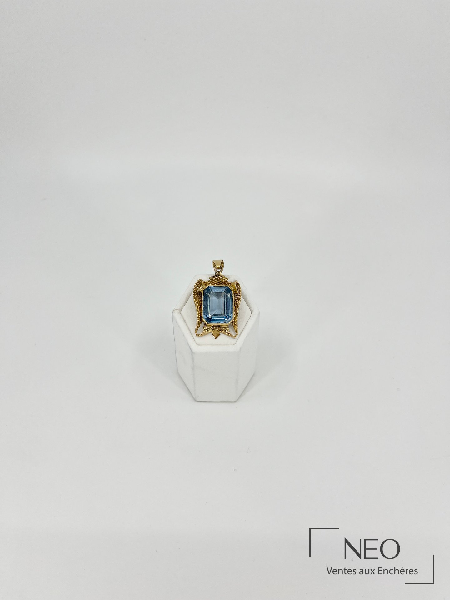 Pendentif en or jaune orné d’une aigue-marine rectangulaire sur support blanc
