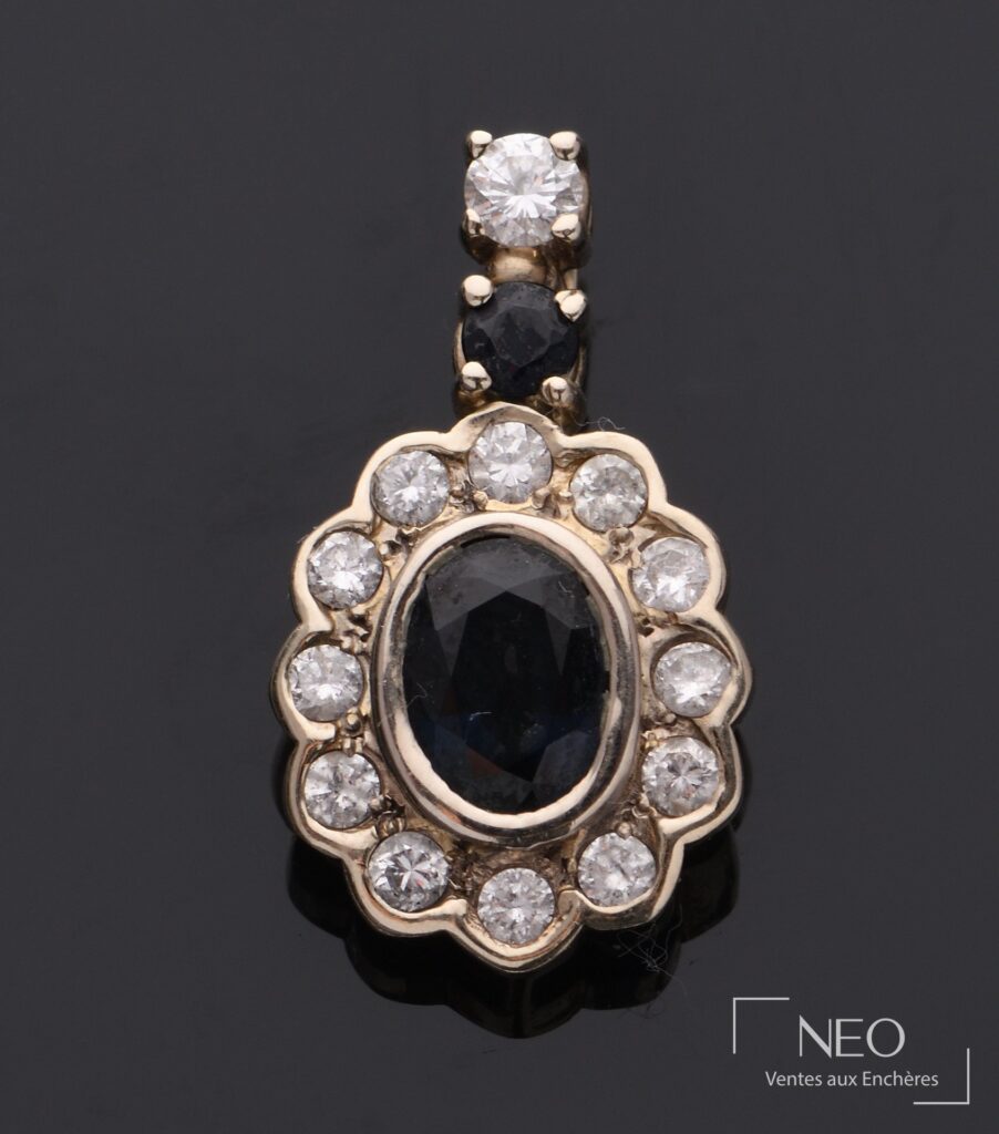 Pendentif ovale en or gris serti d'une pierre bleue entourée de diamants