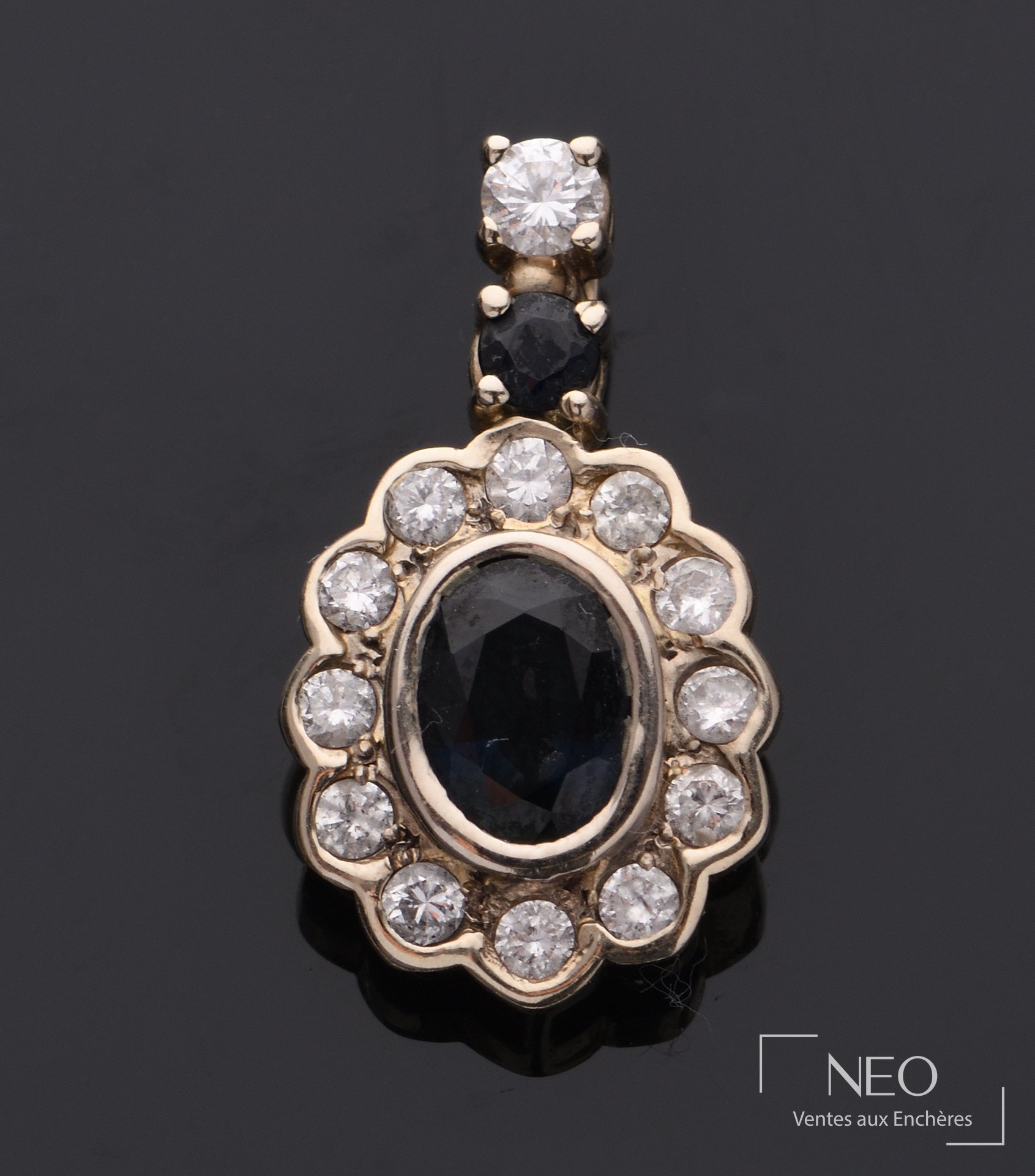 Pendentif ovale en or gris serti d'une pierre bleue entourée de diamants