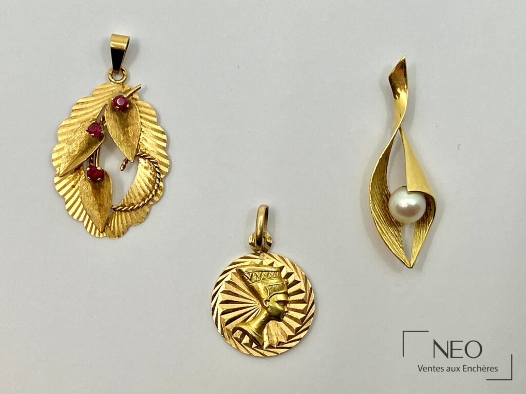 Trois pendentifs en or jaune 18 carats posés sur fond clair