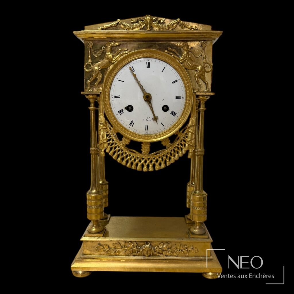 Pendule portique en bronze doré avec cadran rond et décor de lévriers