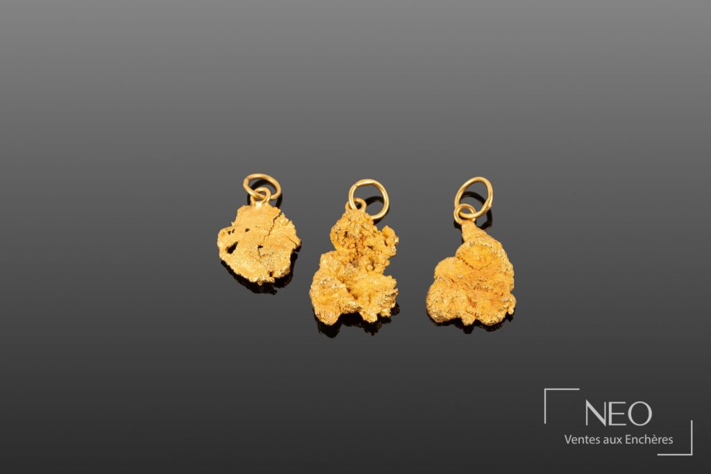 Trois pépites en or jaune montées en pendentif sur fond gris