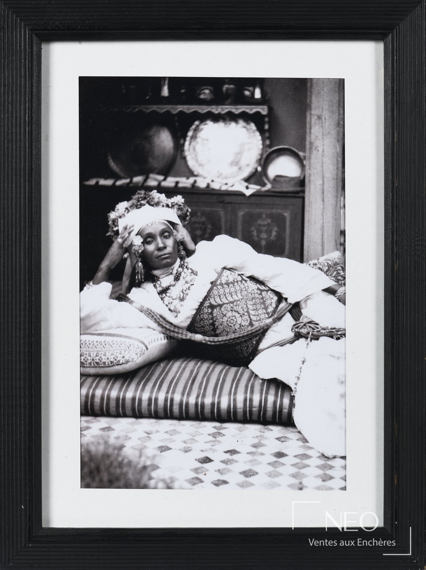 Photographie encadrée en noir et blanc montrant une femme allongée dans un intérieur