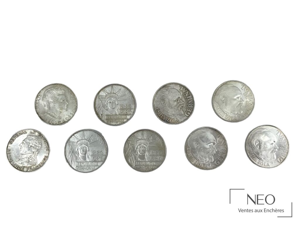 Neuf pièces de 100 francs en argent disposées sur fond blanc