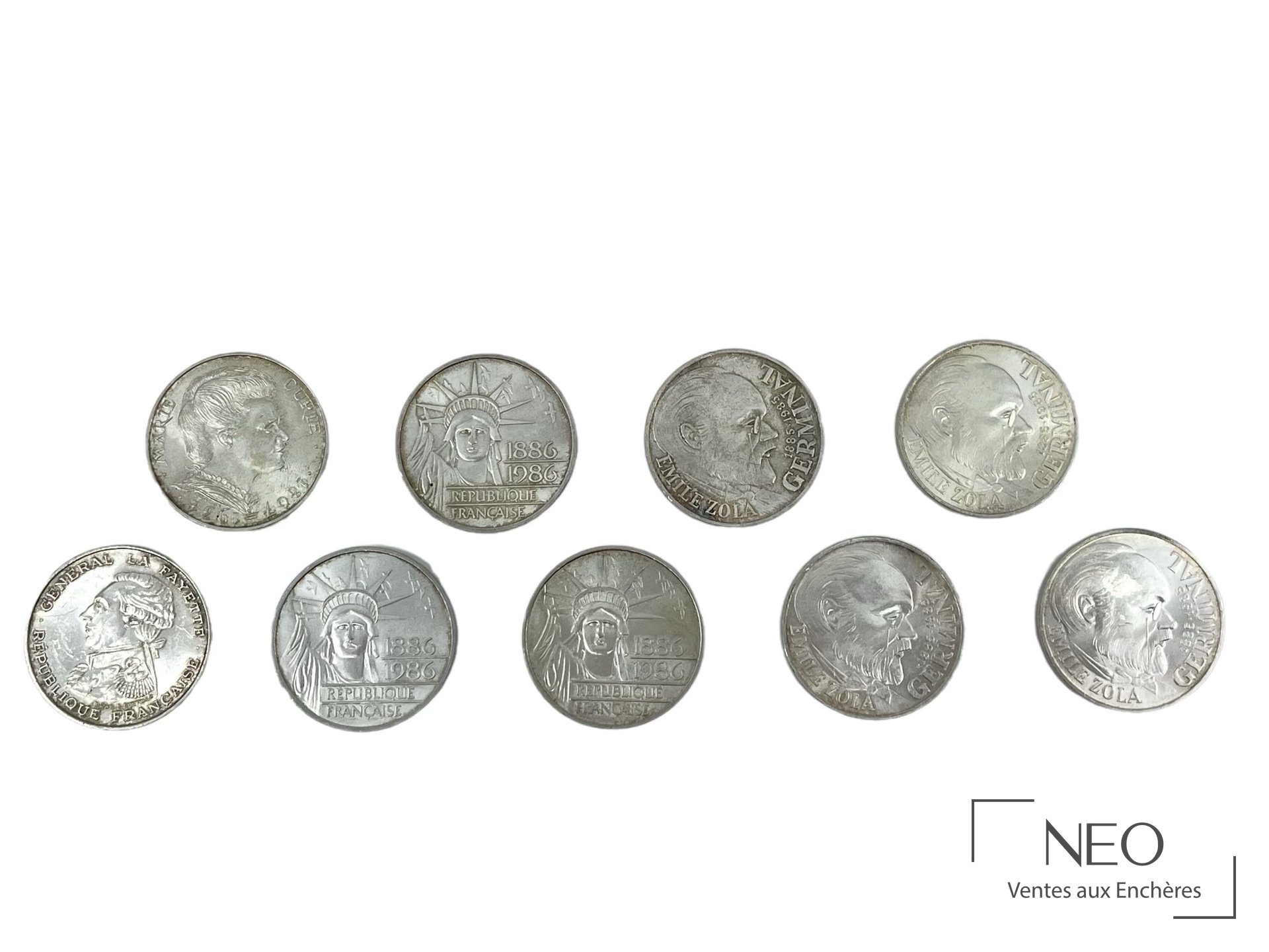 Neuf pièces de 100 francs en argent disposées sur fond blanc
