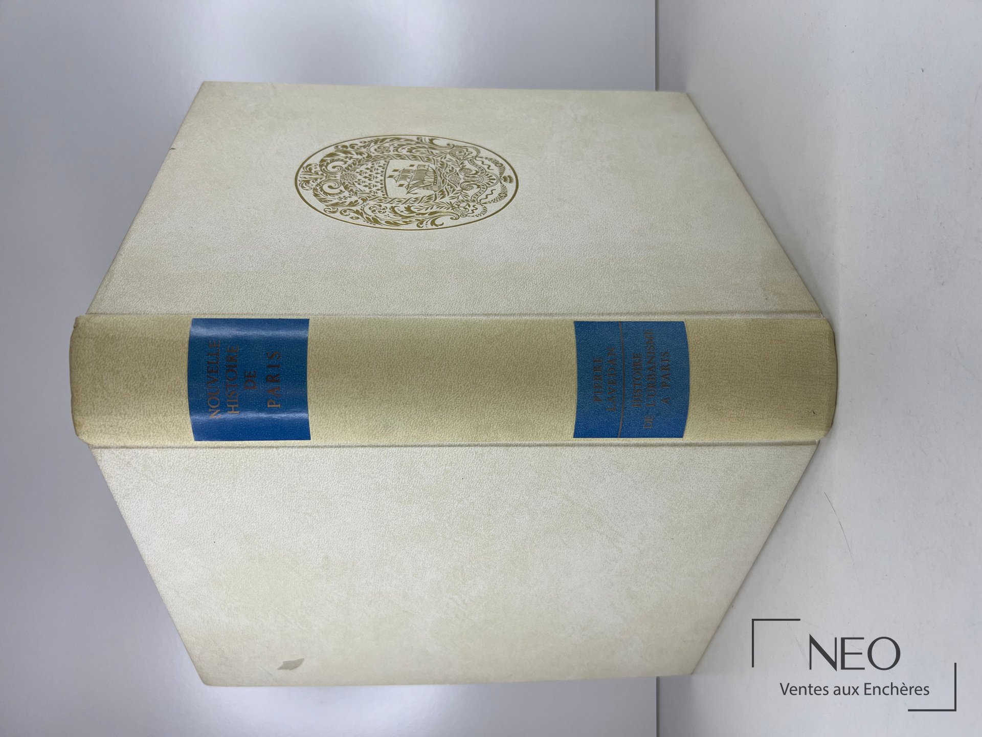 Couverture rigide beige d'un livre avec décor central doré et dos bleu
