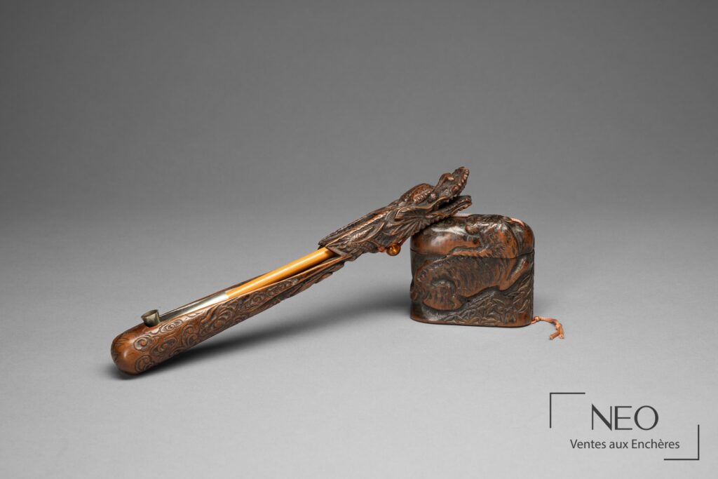 Pipe en bambou et porte-pipe sculpté posés avec l'inro en bois