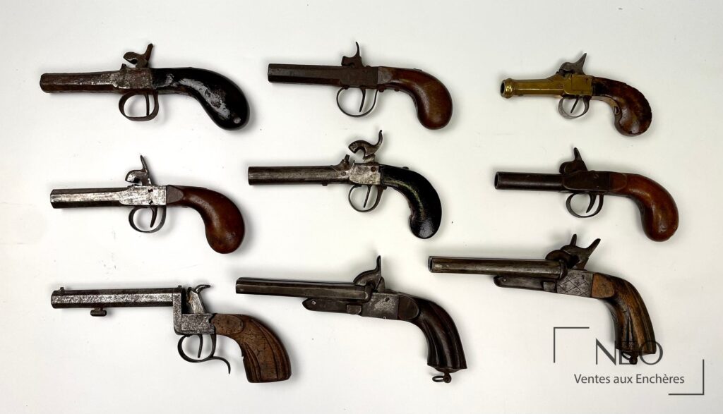 Neuf pistolets anciens présentés de dessus sur fond blanc
