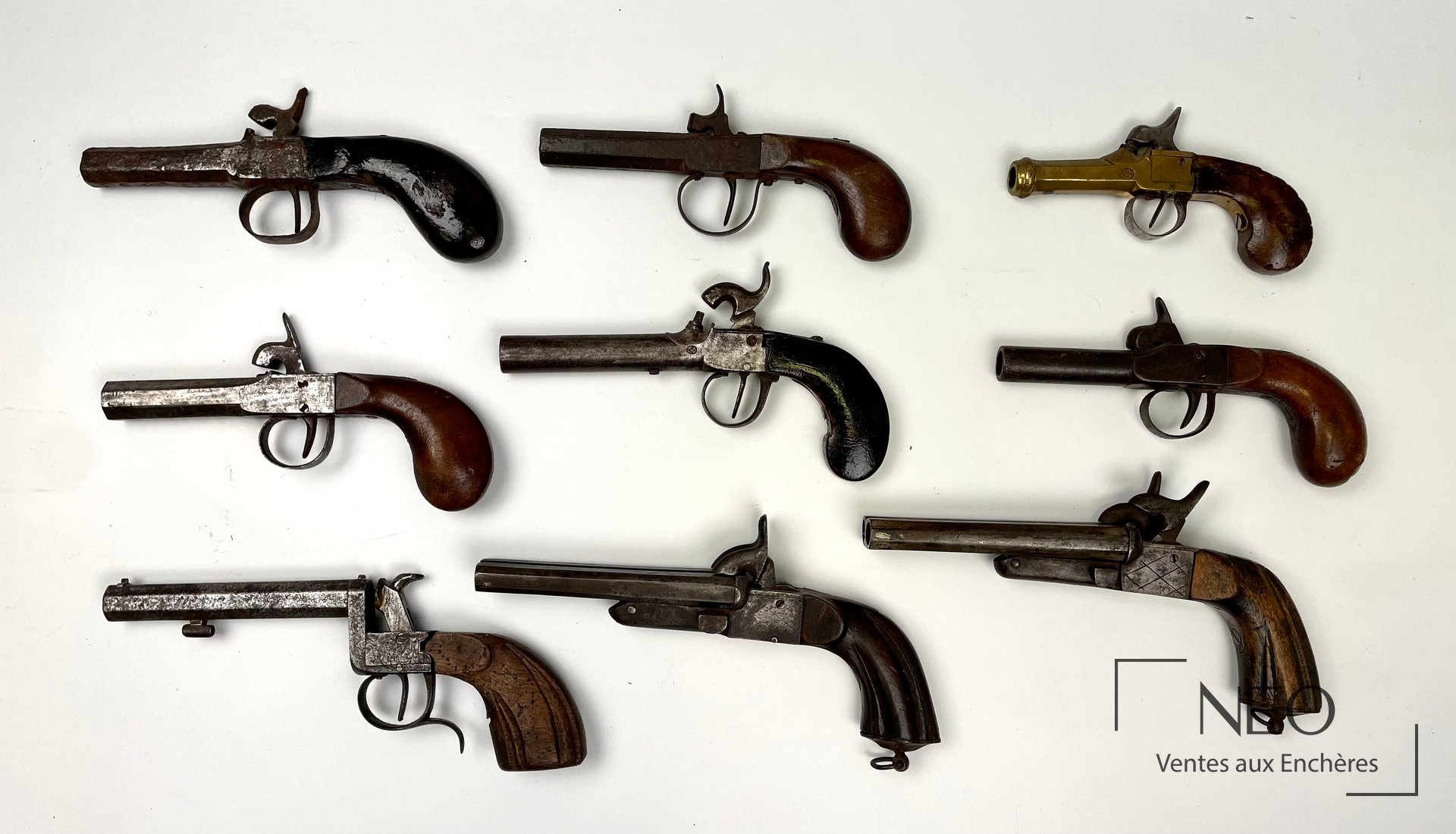 Neuf pistolets anciens présentés de dessus sur fond blanc