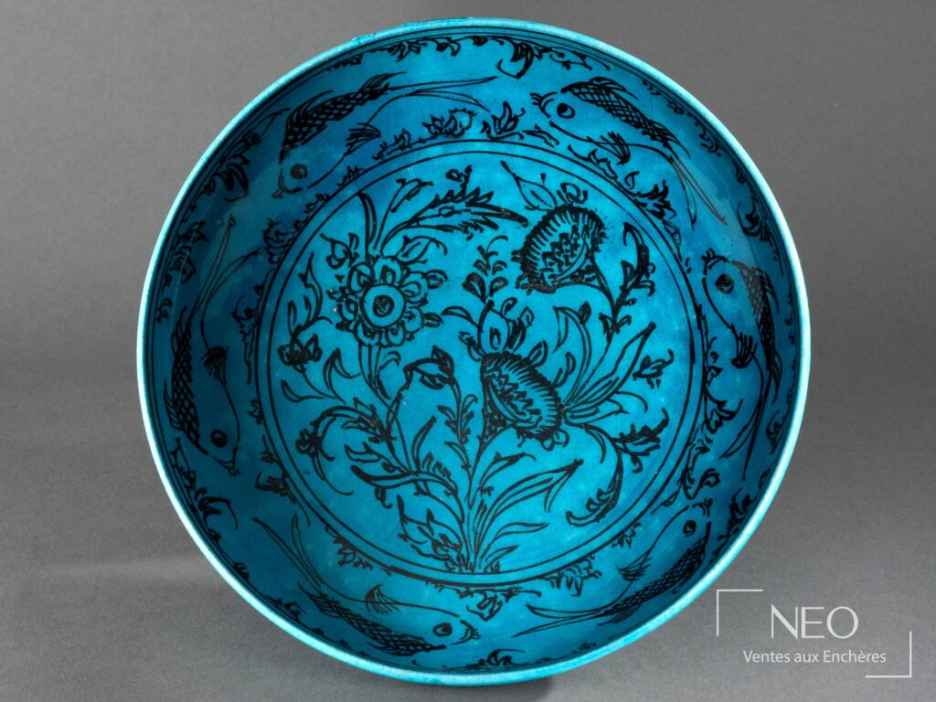 Plat circulaire persan en faïence bleu turquoise au décor noir de bouquet floral et poissons