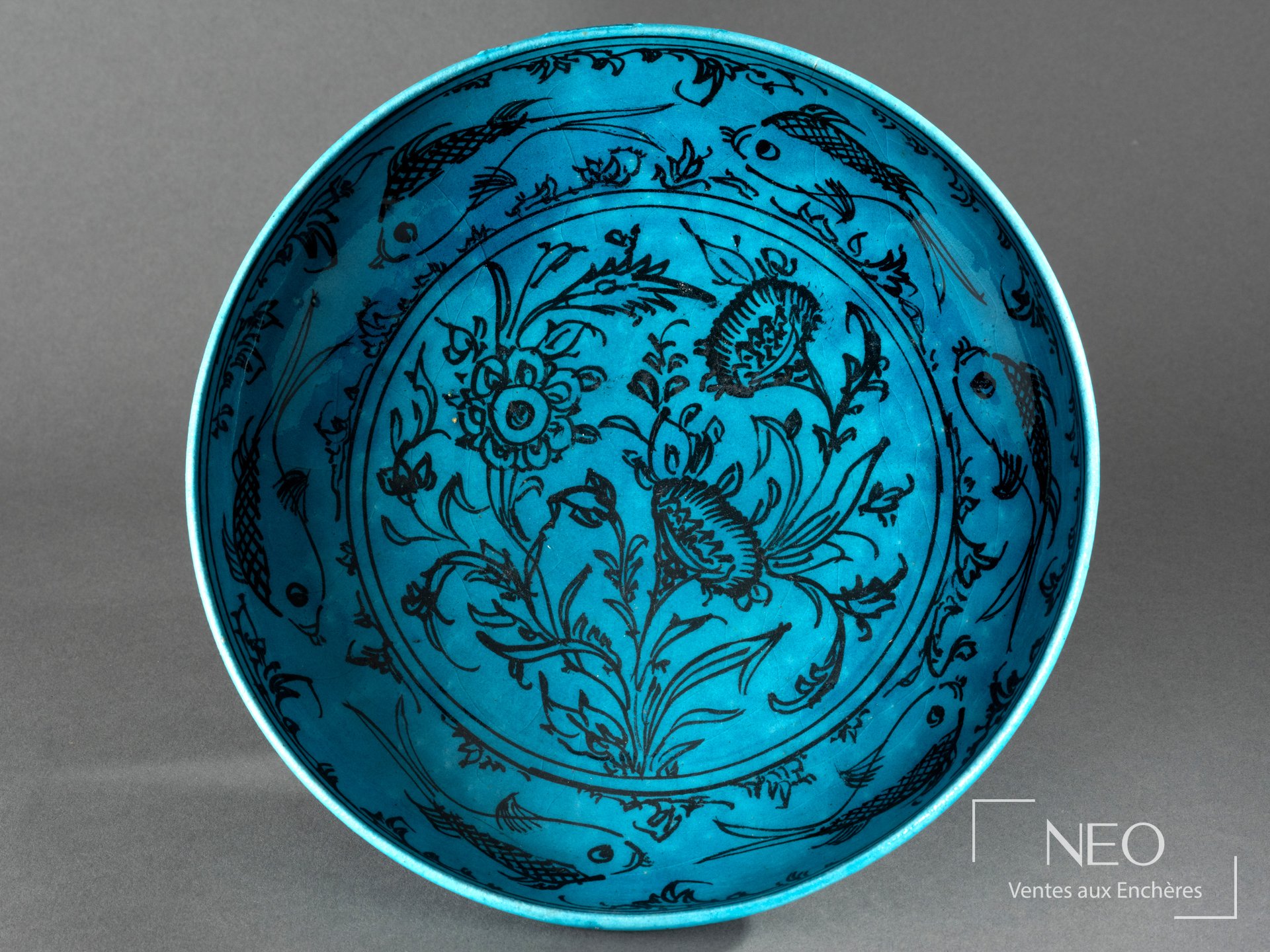 Plat circulaire persan en faïence bleu turquoise au décor noir de bouquet floral et poissons