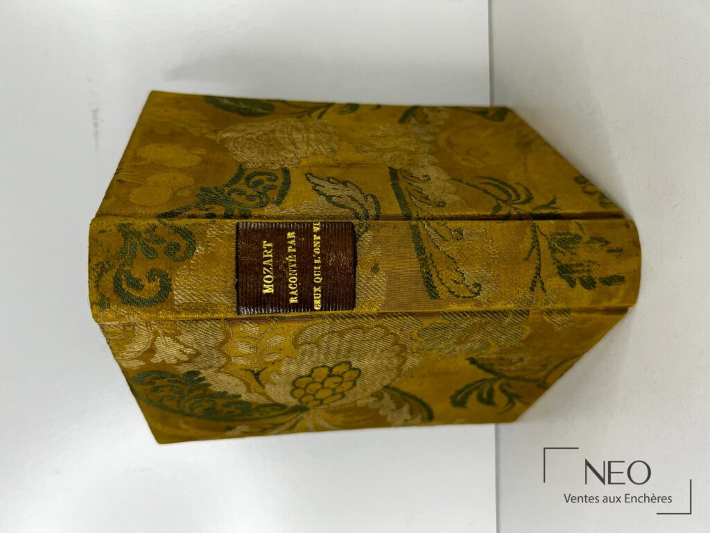 Livre relié de couverture jaune ornée de motifs floraux avec titre au dos.