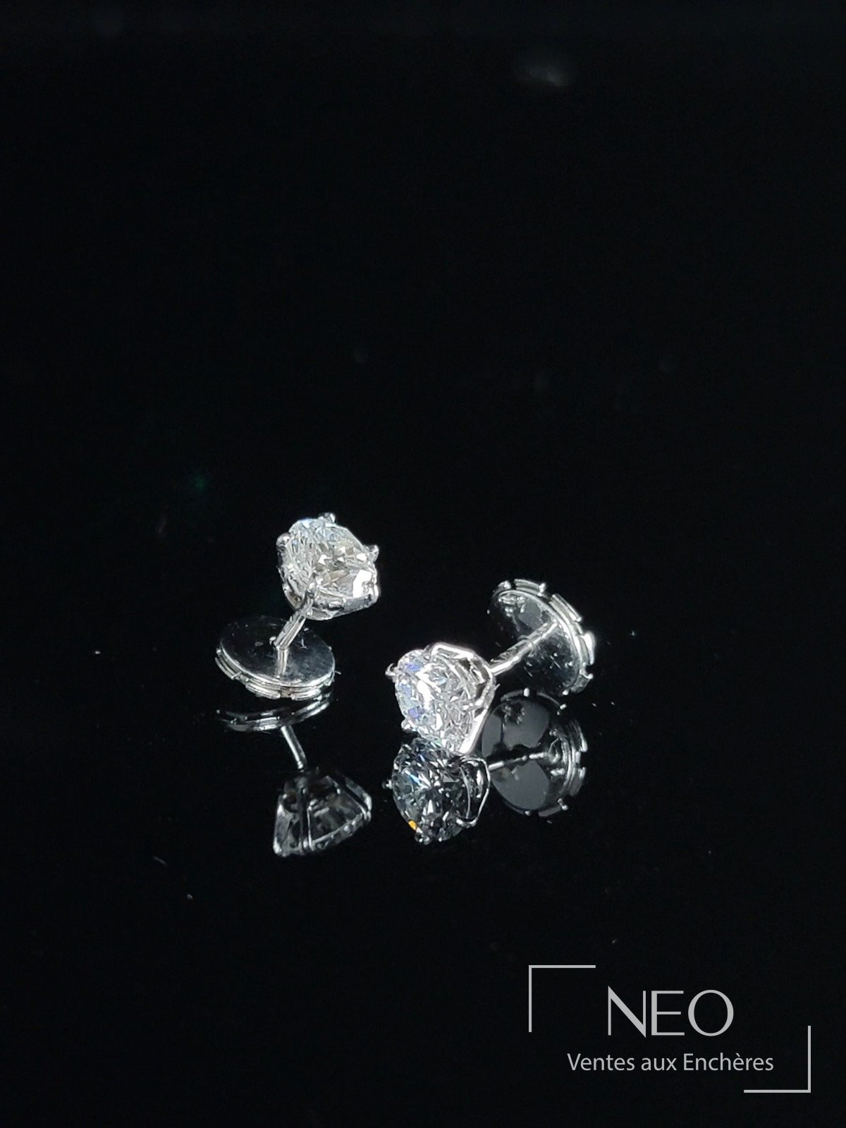 Paire de puces d'oreilles en or gris serties de diamants sur fond noir