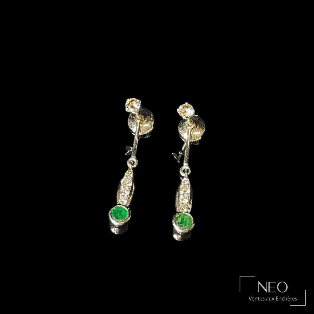 Paire de puces d'oreilles en or gris avec diamants et pampilles serties d'émeraudes.
