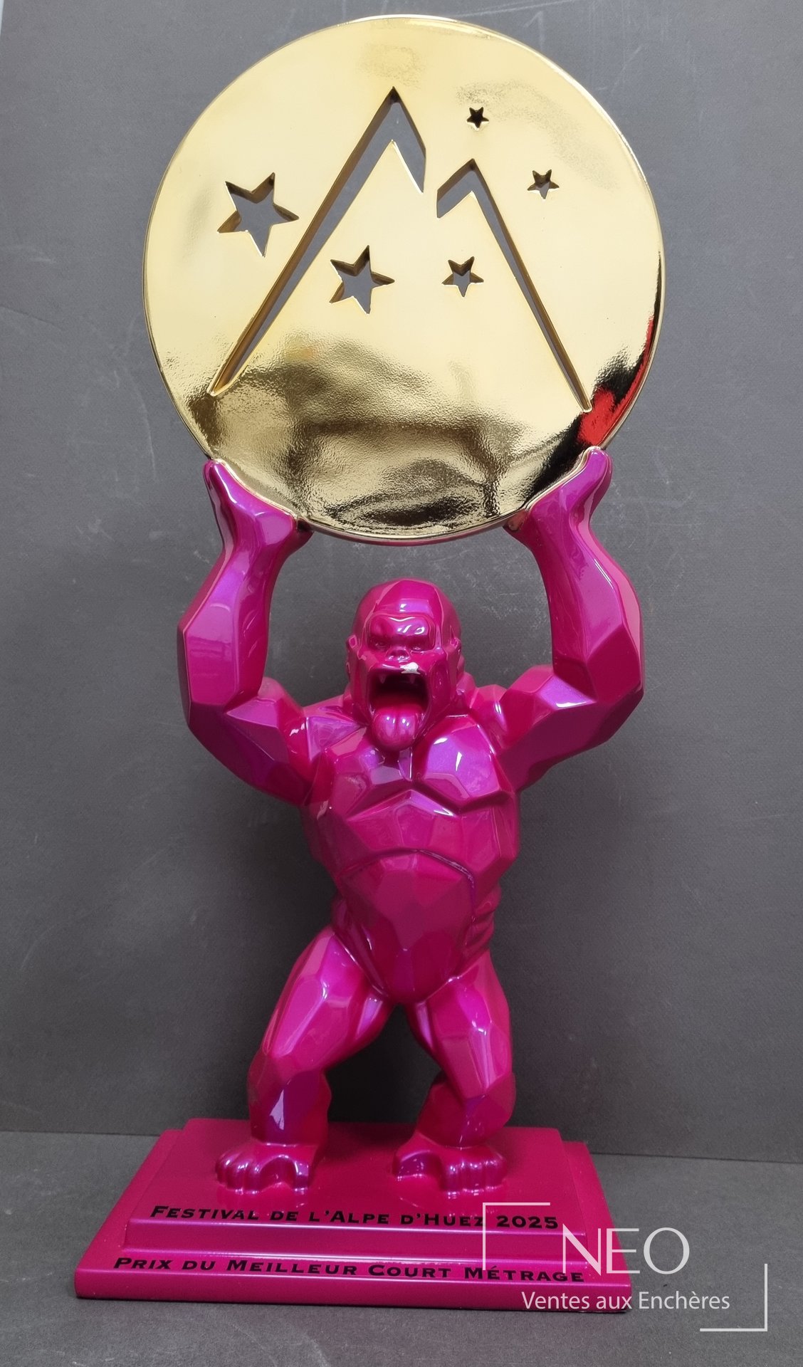 Sculpture Kong rose tenant un disque doré au-dessus de sa tête