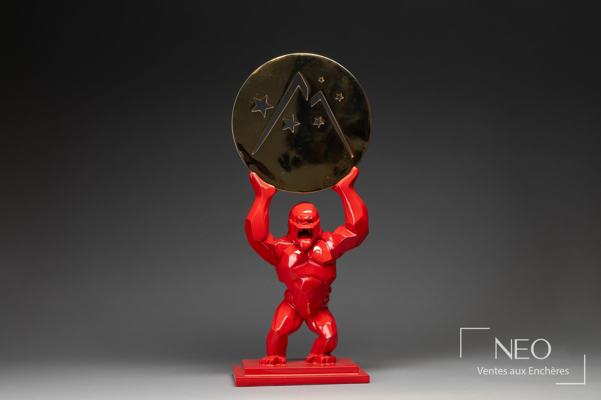 Sculpture Kong rouge tenant un disque doré